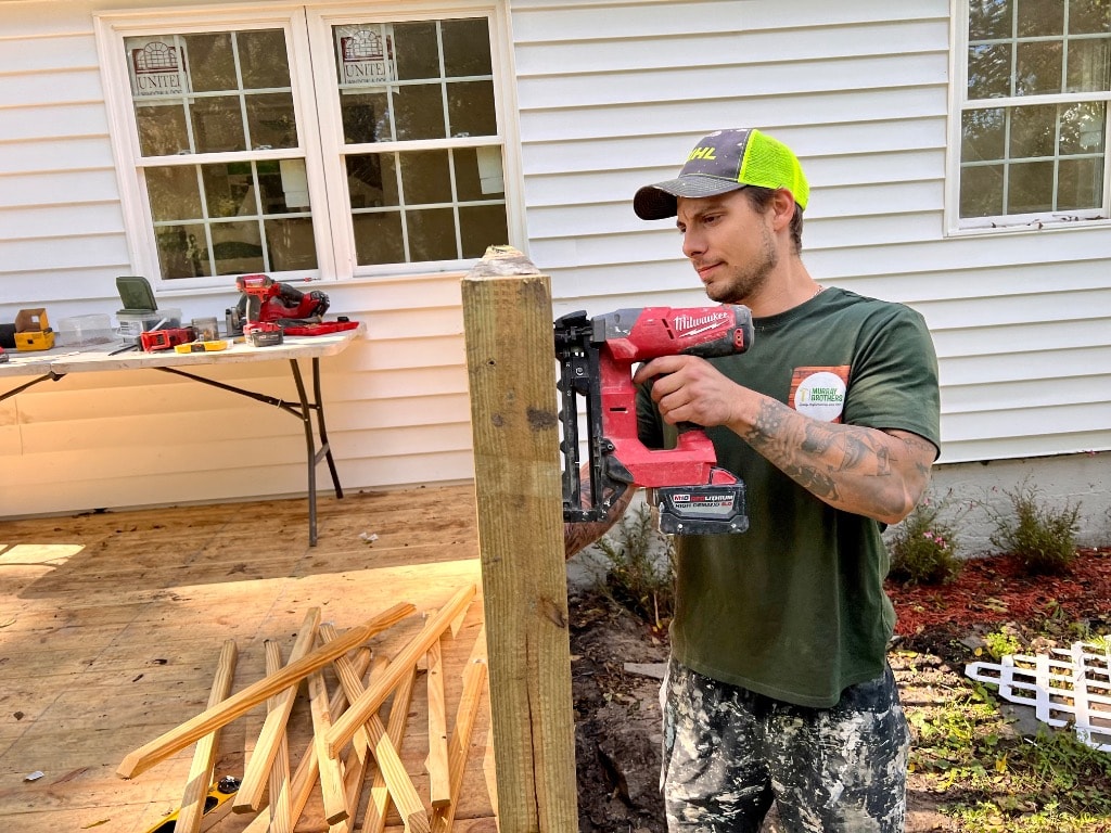Murray Brothers crew member using a Milwaukee nail gun to frame a deck post